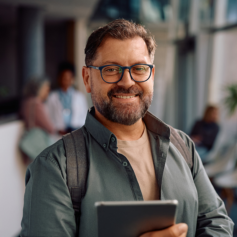 Man wearing glasses, holding a table and smiling at camera.