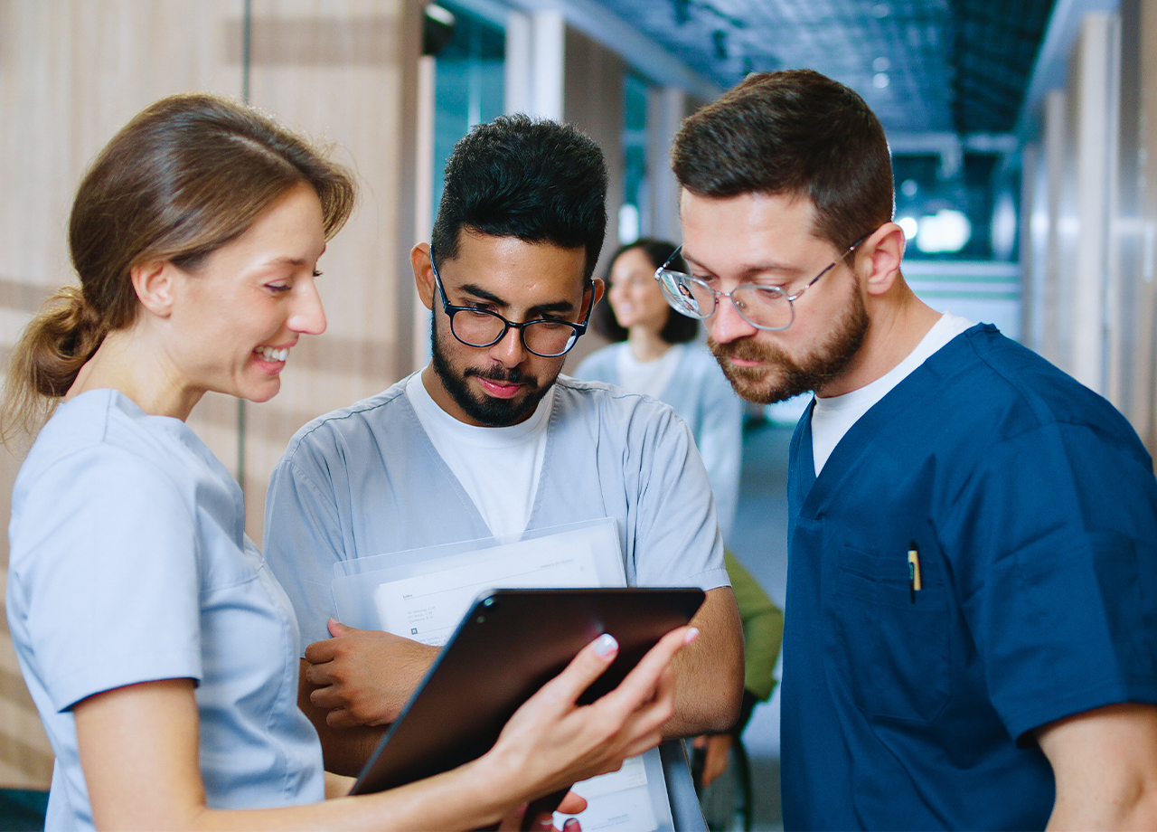 A clinician holding a tablet working with two other clinicians.